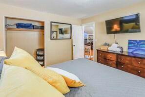 Une chambre à coucher avec un lit, une armoire, une télévision et un miroir.