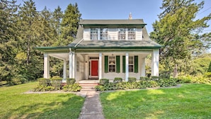 A two-story house with a covered porch, a red door, and a well-maintained lawn. - 3-acre Property: Charming Dutch Country Colonial (Sinking Spring)