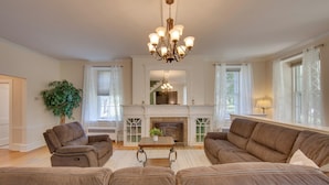A spacious living room with a fireplace, two sofas, a coffee table, and a chandelier. - 3-acre Property: Charming Dutch Country Colonial (Sinking Spring)