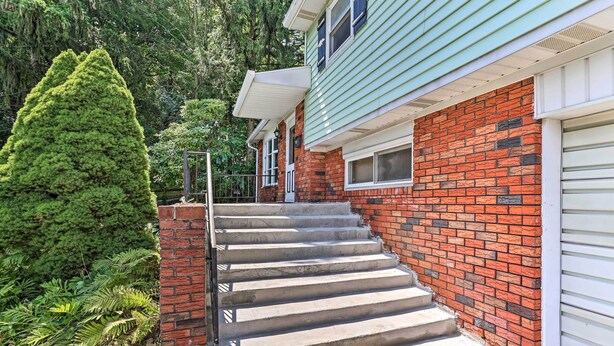 A house with a brick exterior, a green siding section, and a garage door. - Family-friendly Allentown Abode w/ Backyard! (Allentown)