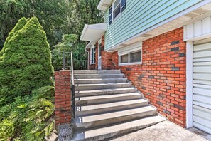 A house with a brick exterior, a green siding section, and a garage door. - Family-friendly Allentown Abode w/ Backyard! (Allentown)