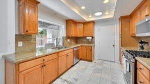 A modern kitchen with wooden cabinets, granite countertops, a stainless steel sink, and a built-in oven. - El Cajon Oasis w/ Backyard 17 Mi to Dtwn San Diego (El Cajon)