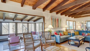 A spacious living room with wooden beams, large windows, a blue sofa, and various chairs. - Hike, Fish & Relax: Family Boone Gem w/ Views! (Boone)