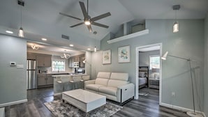 Un vaste espace de vie comprenant une cuisine moderne, un ventilateur de plafond et une grande fenêtre.