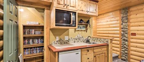 A compact kitchen with wooden cabinets, a microwave, a sink, and a refrigerator.