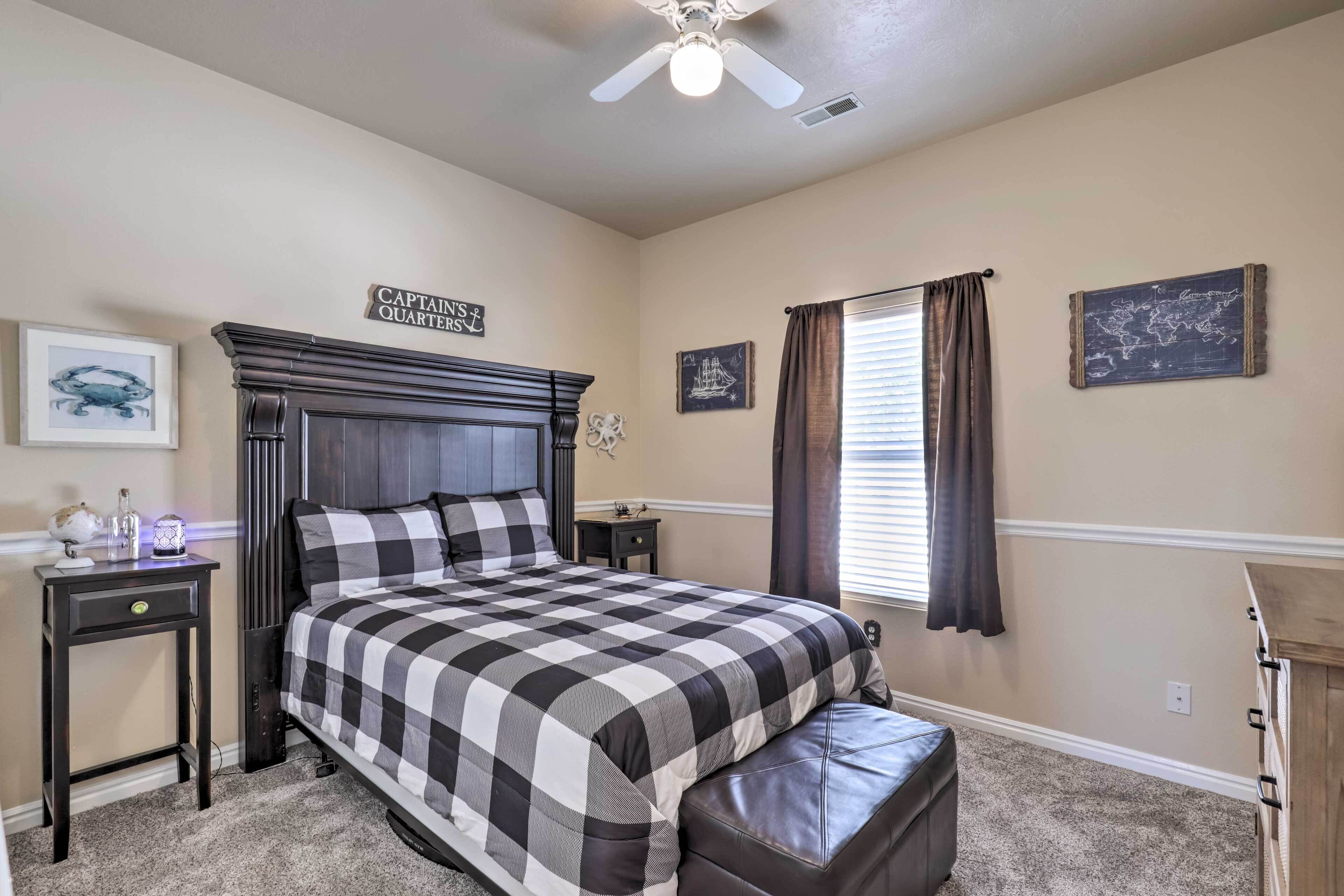 A bedroom with a bed, a nightstand, a dresser, a ceiling fan, and a window with curtains.