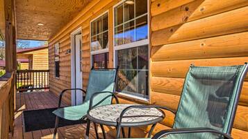 A wooden cabin with a porch, two windows, and two chairs.