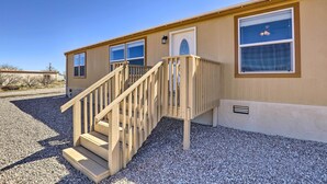A single-story building with a wooden staircase leading to a door with a window. - Desert Escape Off I-10 w/ Over 1 Enclosed Acre! (Benson)