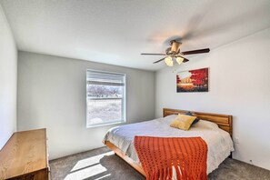 A bedroom with a bed, a ceiling fan, a window, and a painting on the wall. - Desert Escape Off I-10 w/ Over 1 Enclosed Acre! (Benson)