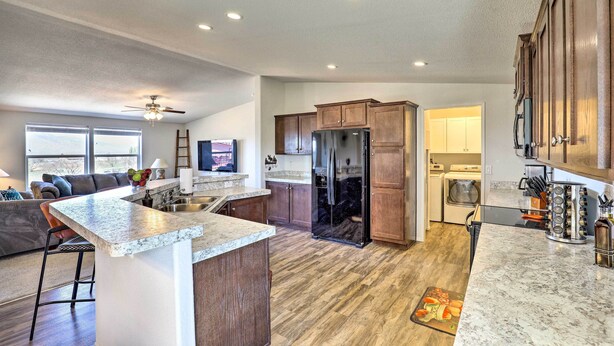 A spacious kitchen with wooden cabinets, a large island, and a built-in refrigerator. - Desert Escape Off I-10 w/ Over 1 Enclosed Acre! (Benson)