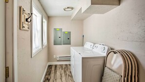 A laundry room with a washing machine, dryer, and stacked laundry baskets.