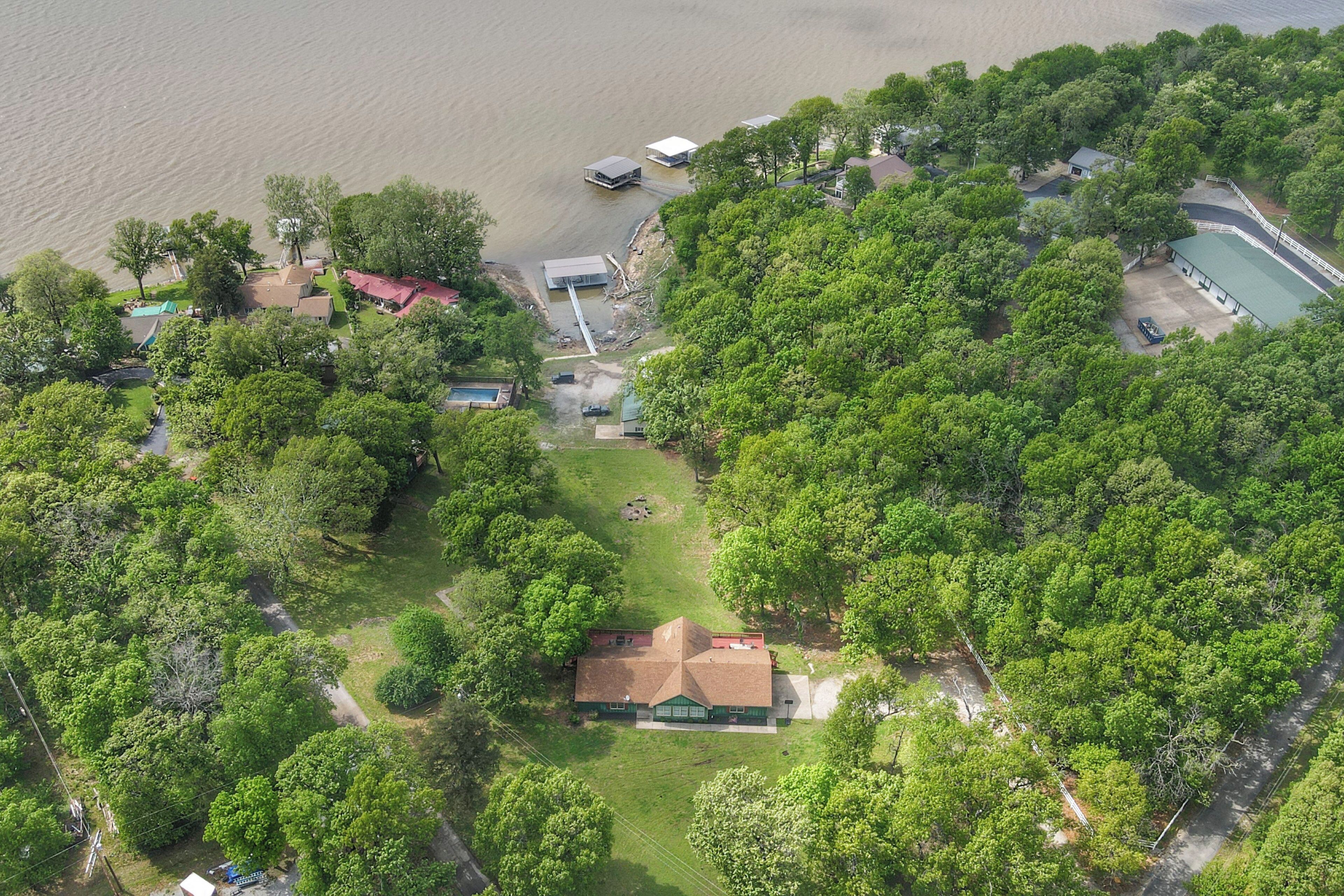 Vista aérea de uma área residencial com uma casa, um cais e uma piscina.