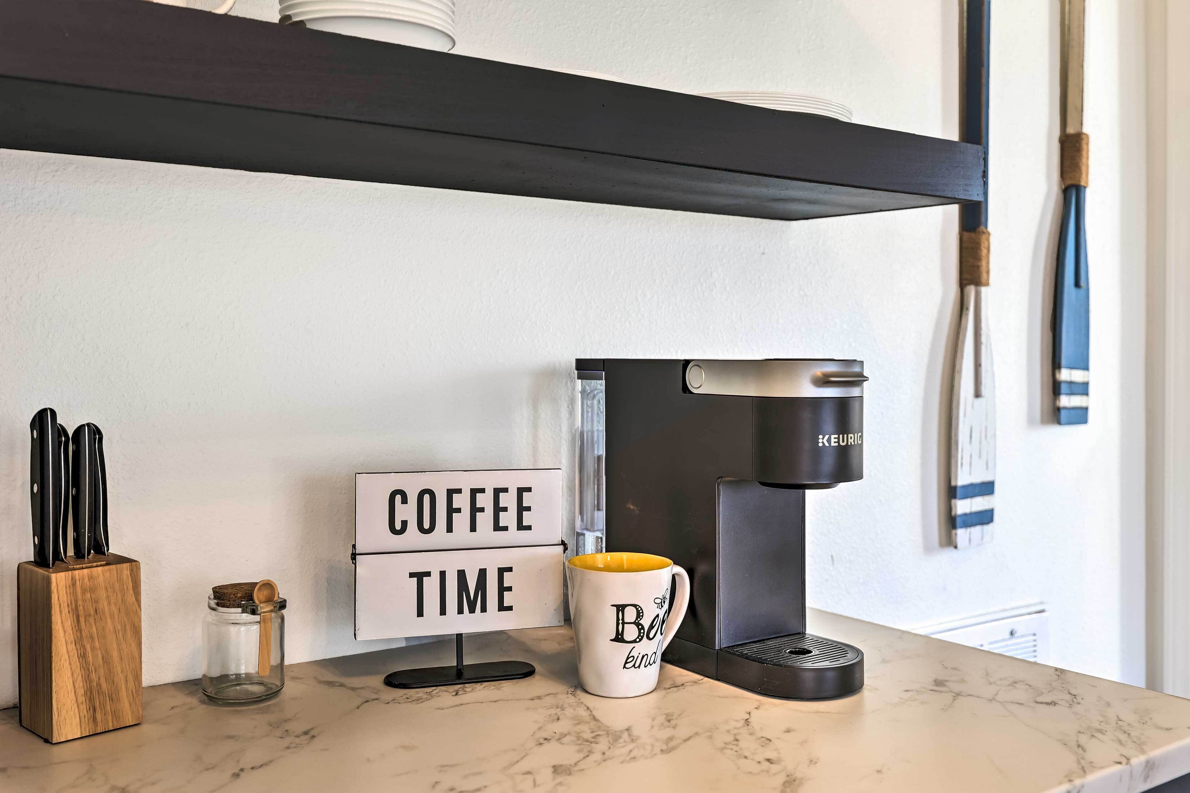 A kitchen counter with a coffee maker, a mug, a knife block, and a jar.