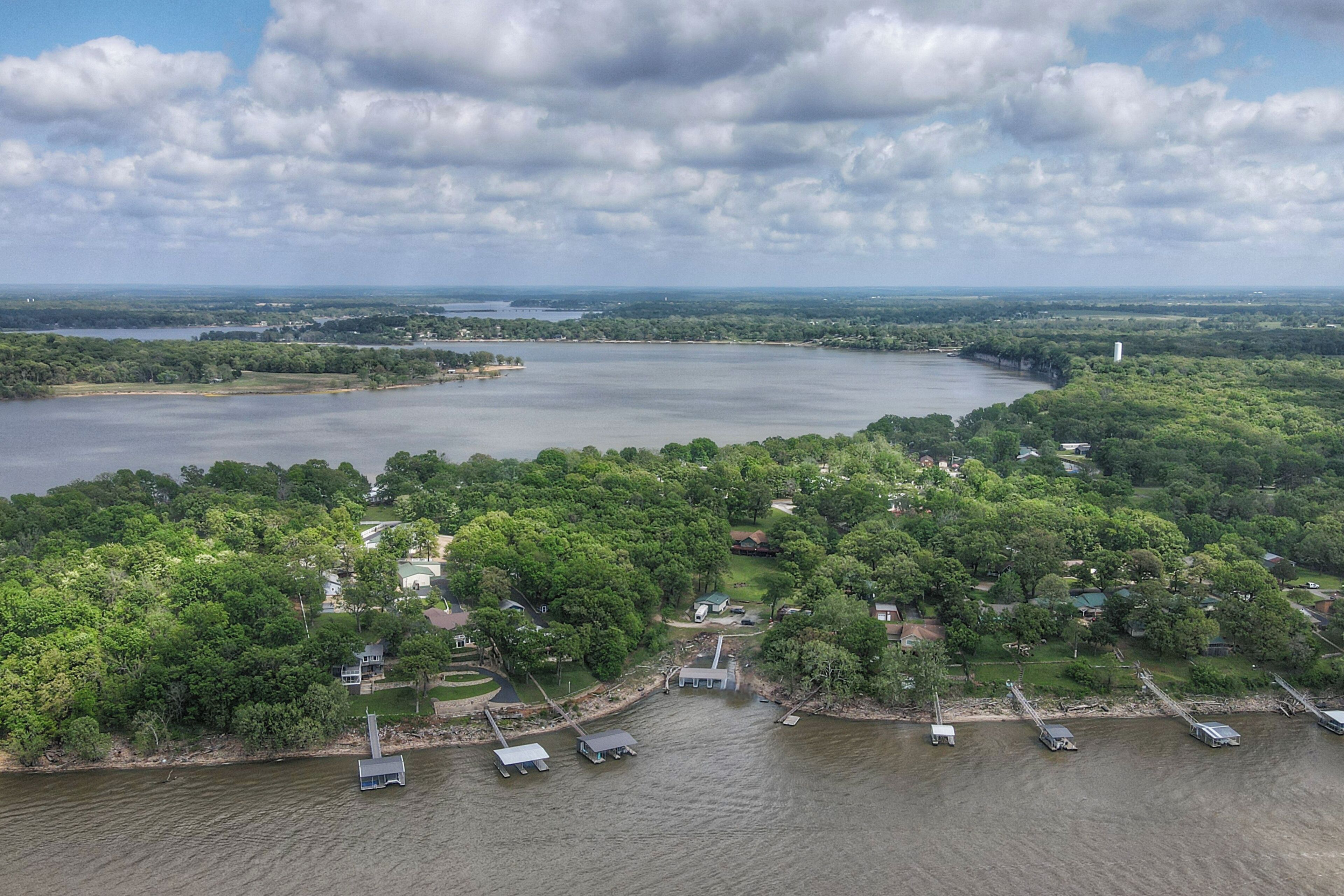 Vue aérienne d’une propriété au bord d’un lac, avec des quais, des bateaux et une forêt dense.