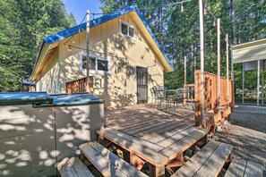 Una terraza de madera con mesas de picnic, un área de estar cubierta y una casa con techo azul.