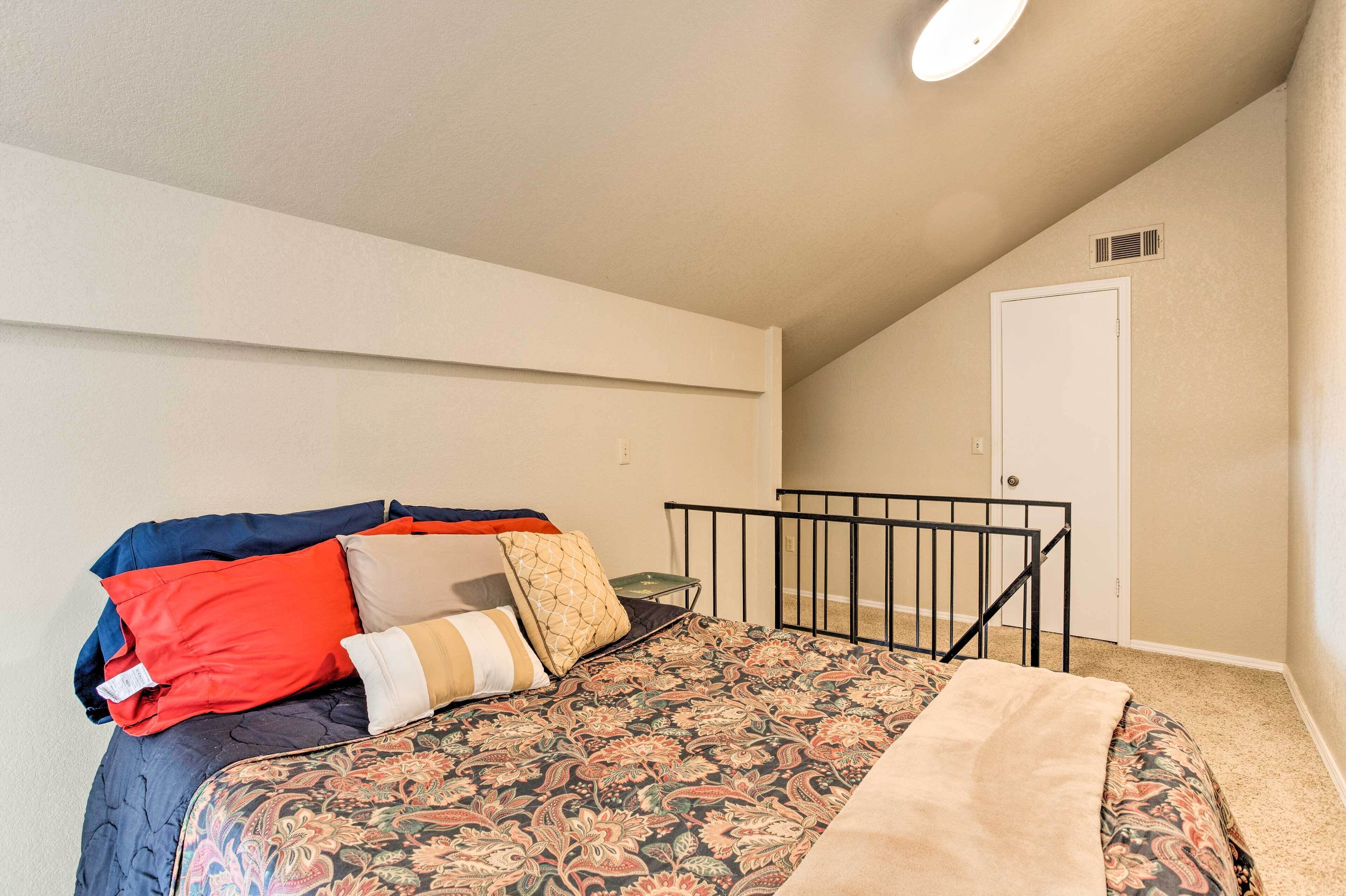 Ein Schlafzimmer mit Bett, Kissen, Decke, einer Tür und einer Deckenleuchte.