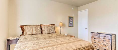 A bedroom with a bed, a nightstand, a dresser, a ceiling fan, and a lamp.
