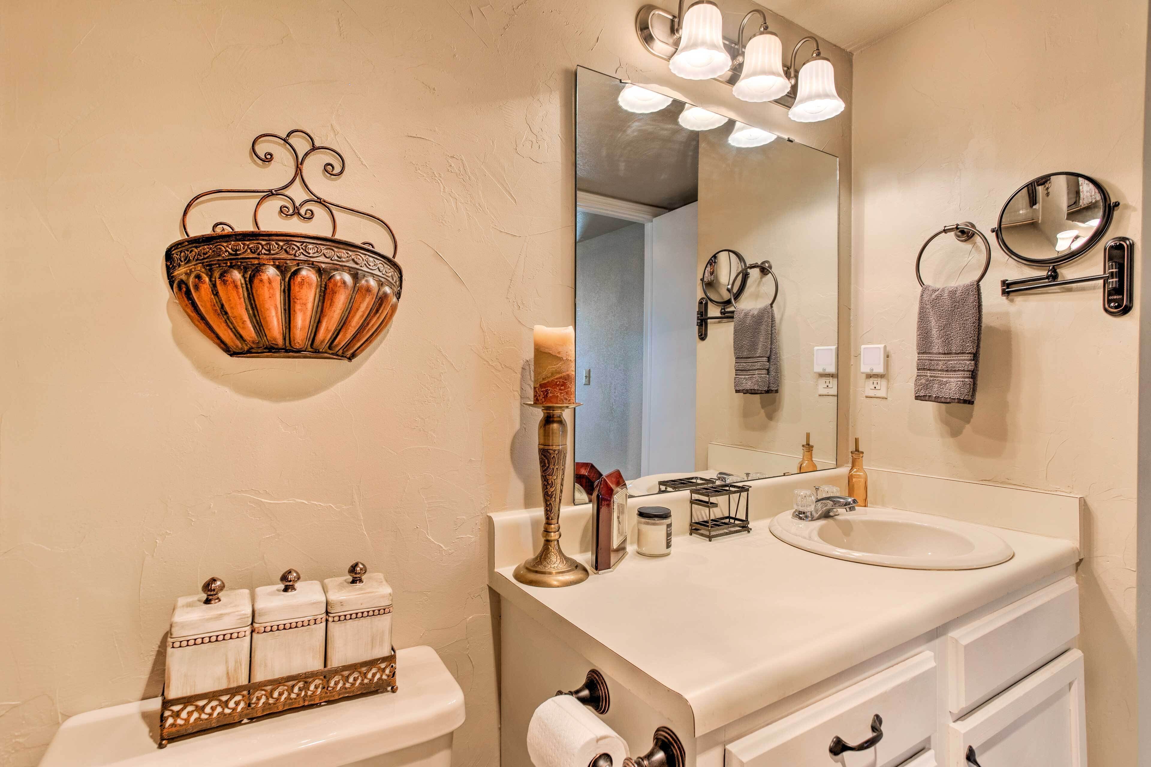 A bathroom with a toilet, sink, mirror, and decorative wall sconces.