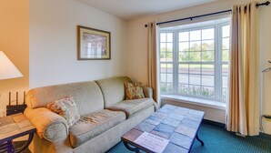 A cozy room with a sofa, a table, and a window with curtains. - Cozy Pigeon Getaway, Close to Public Beaches! (Pigeon)