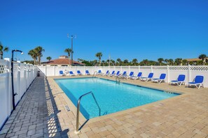 Ein Swimmingpool mit blauen Stühlen und einem weißen Zaun.