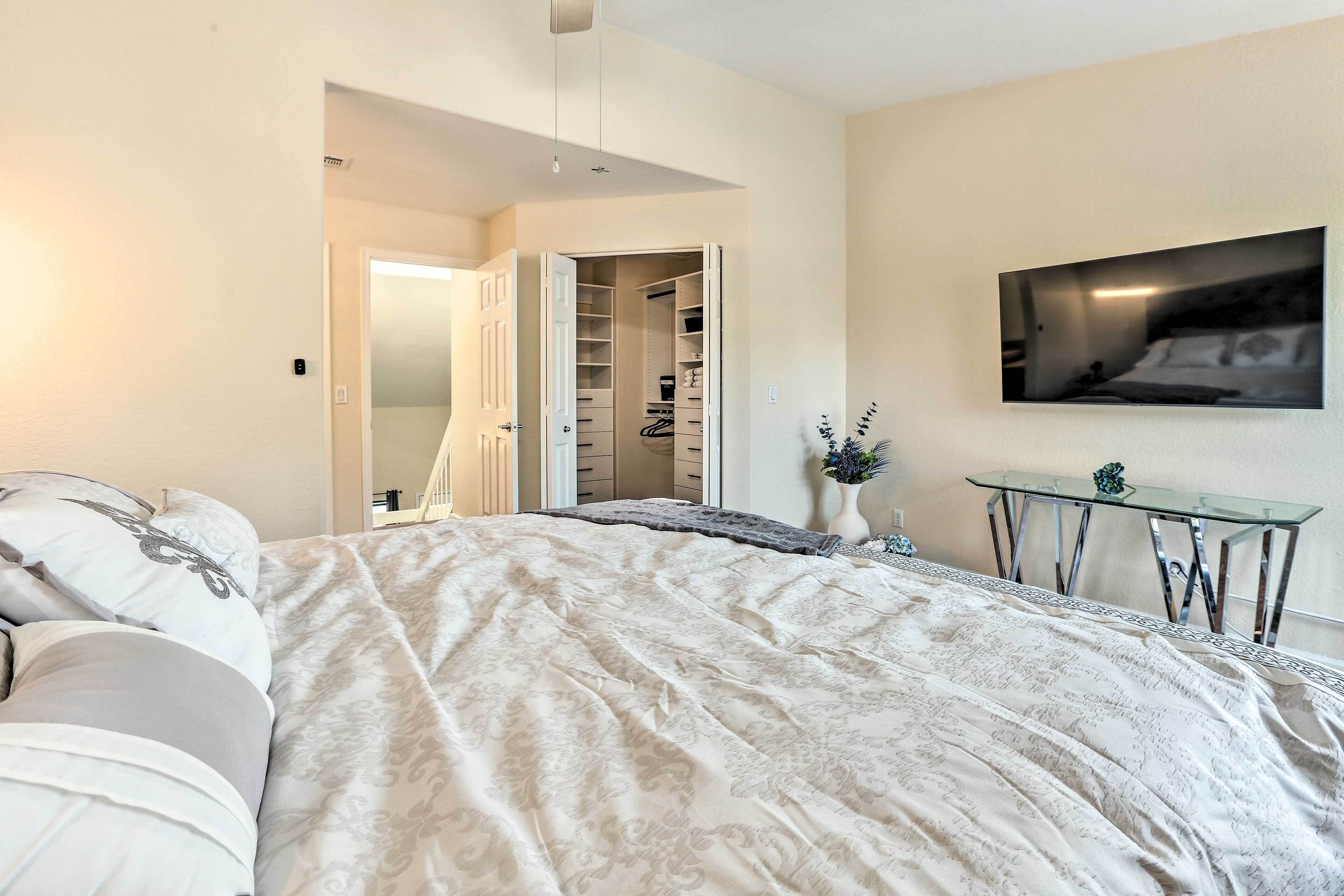 Une chambre à coucher avec un grand lit, un placard, une table en verre et un téléviseur fixé au mur.