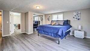 A bedroom with a bed, bedside table, and a door leading to another room. - Whitesburg Vacation Home w/ Glass-enclosed Porch (Whitesburg)