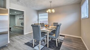 A dining area with a rectangular table, grey upholstered chairs, a chandelier, and a patterned rug. - Whitesburg Vacation Home w/ Glass-enclosed Porch (Whitesburg)