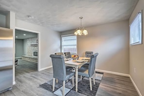 A dining area with a rectangular table, grey upholstered chairs, a chandelier, and a patterned rug. - Whitesburg Vacation Home w/ Glass-enclosed Porch (Whitesburg)