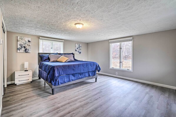 A bedroom with a bed, nightstand, and artwork on the walls.
