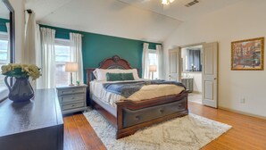 Een slaapkamer met een bed, nachtkastjes, een dressoir, een vaas met bloemen en een schilderij aan de muur.