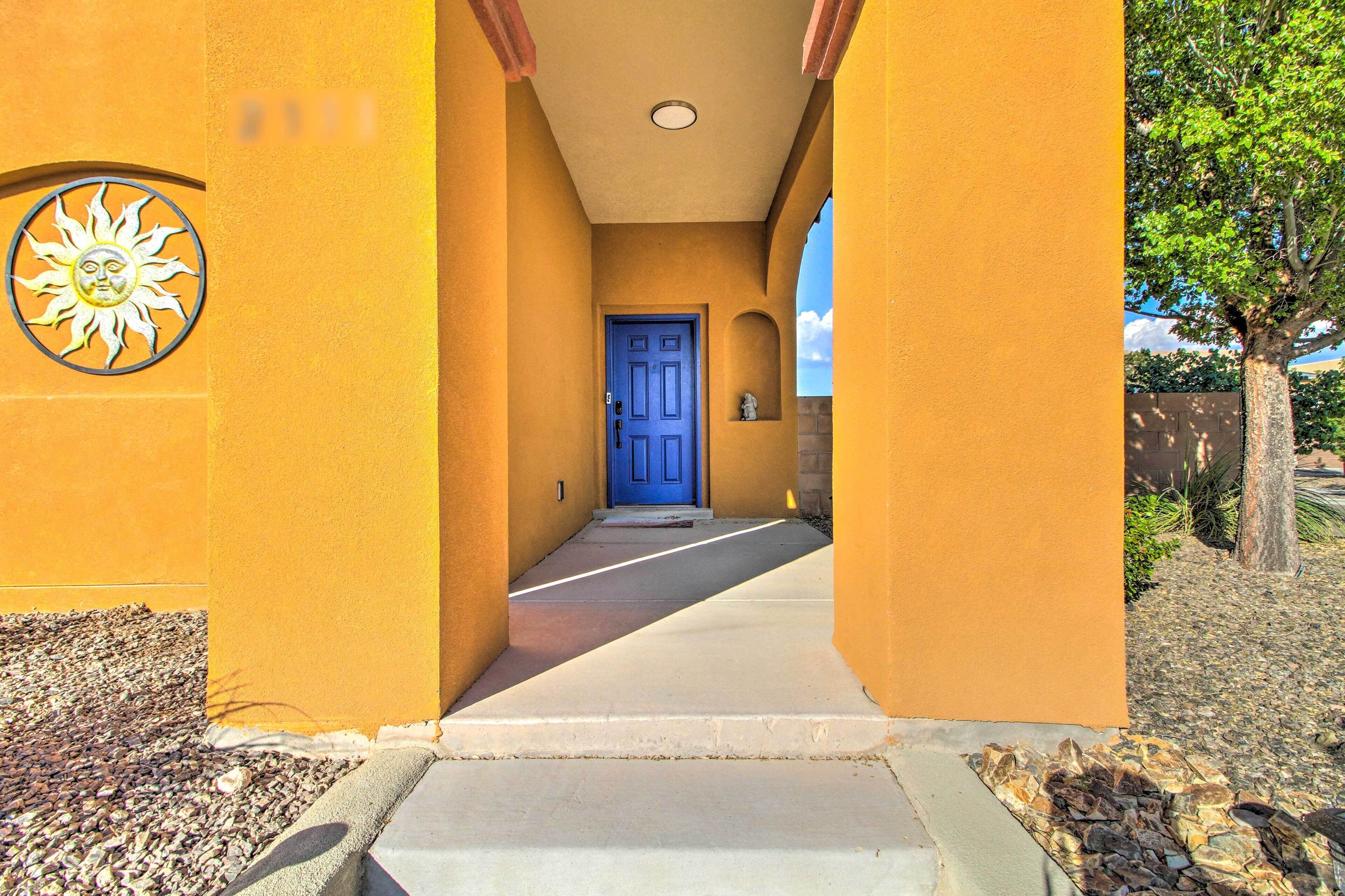 Un pasillo con una puerta azul, paredes amarillas y un emblema de sol.