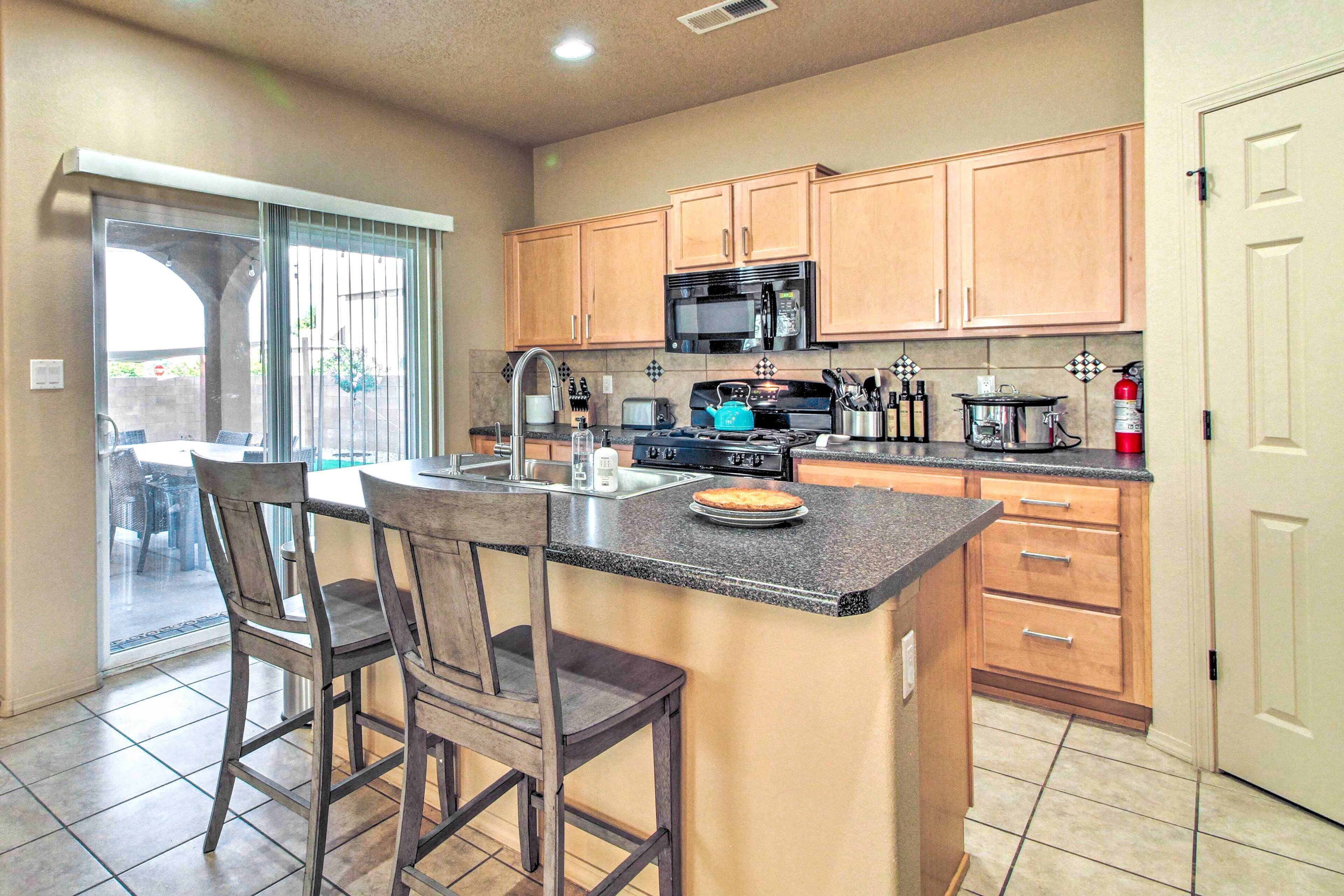 A kitchen with wooden cabinets, a granite countertop, a microwave, and a stove.
