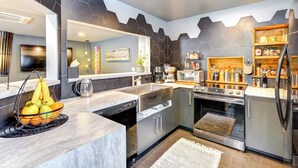 A modern kitchen with a central island, stainless steel appliances, and a hexagonal tile backsplash. - 'little House on the Lot' Dryden Townhome: Pets OK (Dryden)