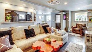 A modern living room with a sectional sofa, wooden coffee tables, and a leather armchair. - 'little House on the Lot' Dryden Townhome: Pets OK (Dryden)