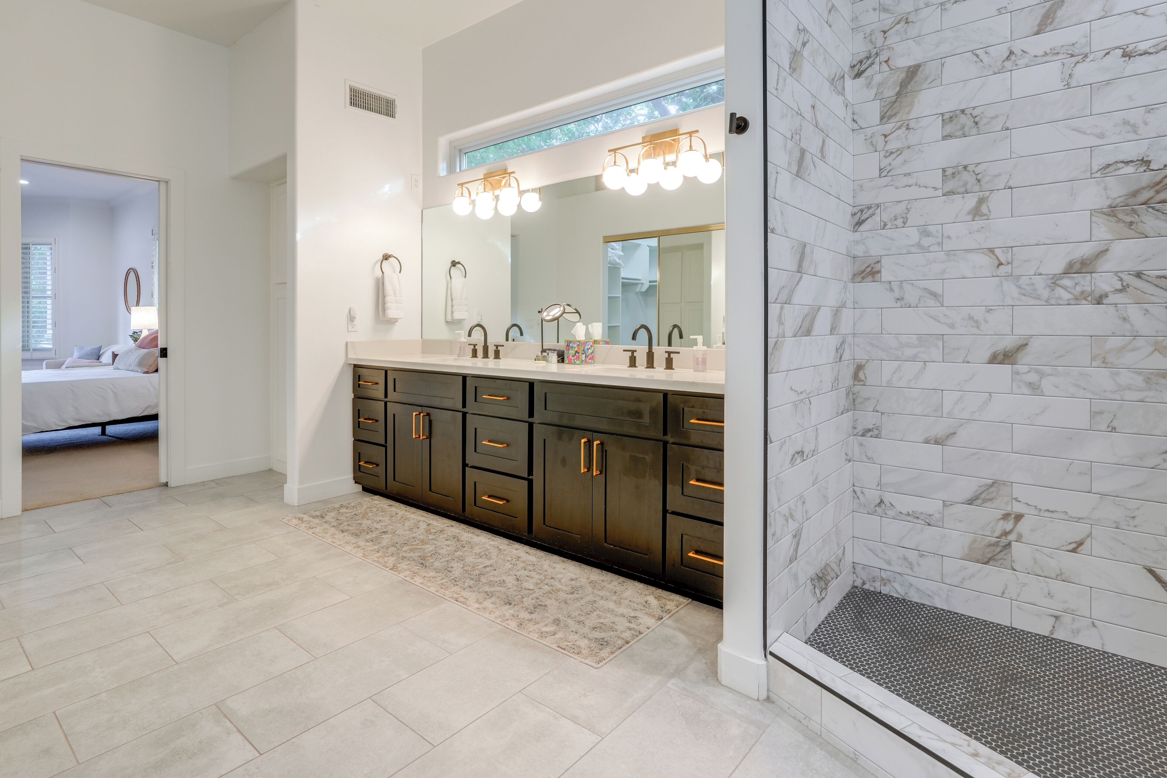 A modern bathroom with a large mirror, dual sinks, and dark cabinetry.
