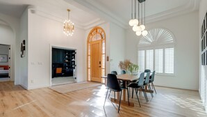 A spacious dining area with a wooden table and chairs, a large window with blinds, and a decorative wooden door. - Pool Table, Putting Green: Luxury Oasis in Mesa (Mesa)
