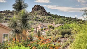 A desert landscape with a prominent rock formation, a house with a tiled roof, and various desert plants. - Gold Canyon Getaway w/ Golf + Community Perks (Gold Canyon)