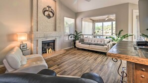 A spacious living room with a fireplace, a ceiling fan, and a large window. - Gold Canyon Getaway w/ Golf + Community Perks (Gold Canyon)