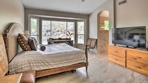 A bedroom with a large bed, a TV, wooden furniture, and a view through the window. - Gold Canyon Getaway w/ Golf + Community Perks (Gold Canyon)