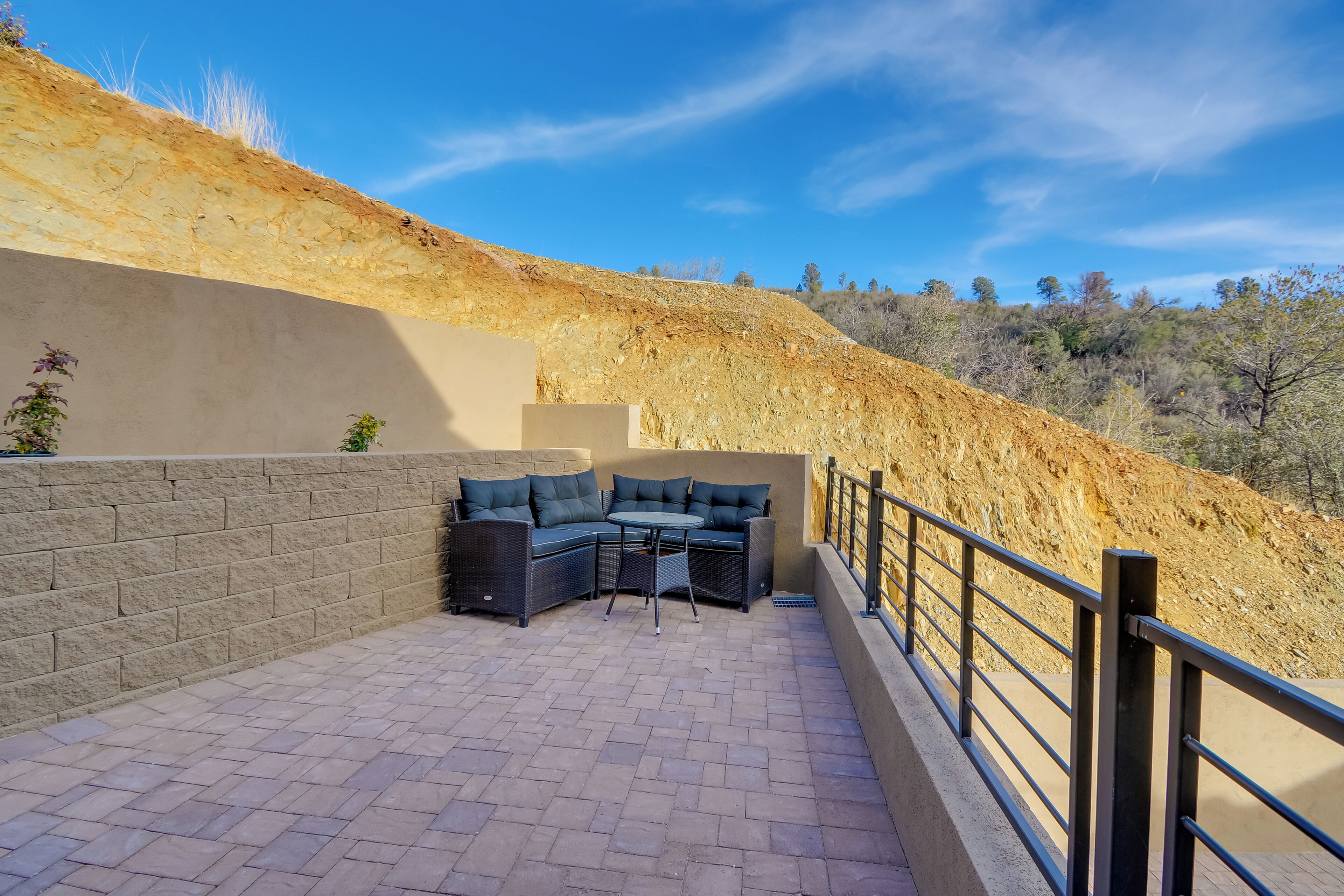 A patio with a built-in seating area and a view of a hillside.