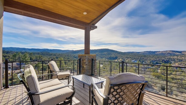 A wooden deck with outdoor furniture and a stone fireplace, overlooking a mountainous landscape. - Prescott Vacation Rental w/ Game Room & Mtn Views! (Prescott)