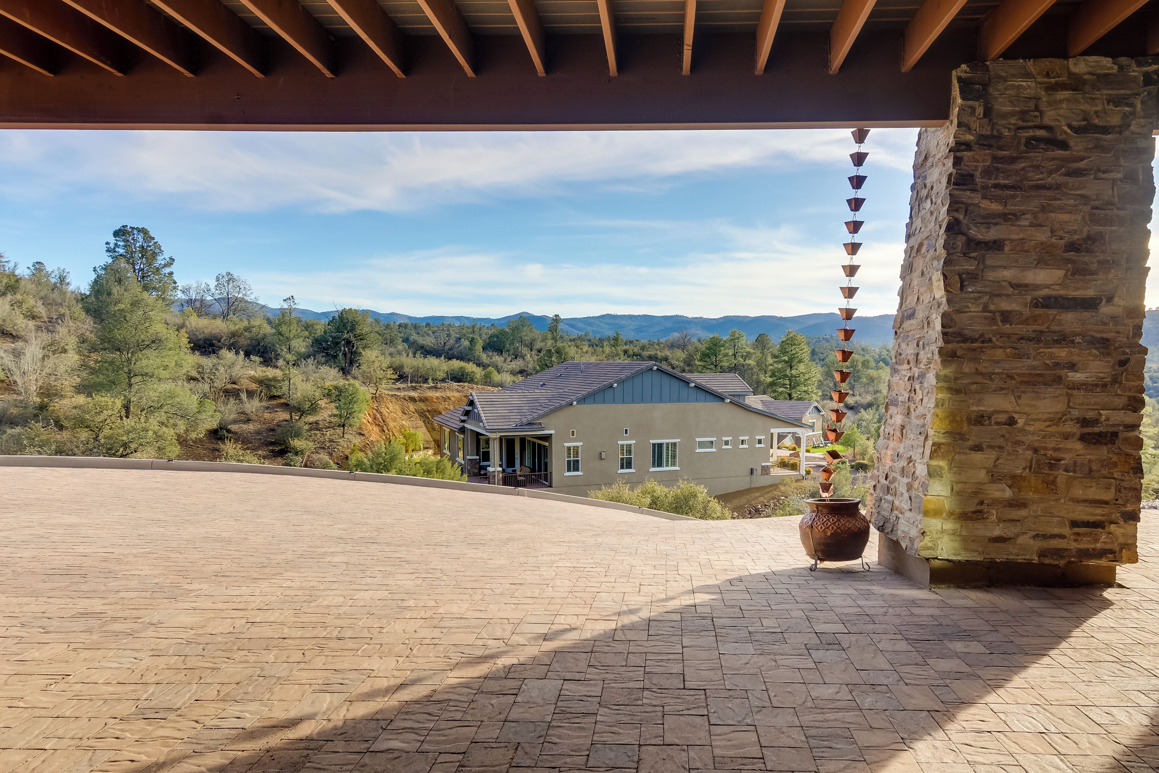 A covered patio area with a stone wall and a view of a house in the background.