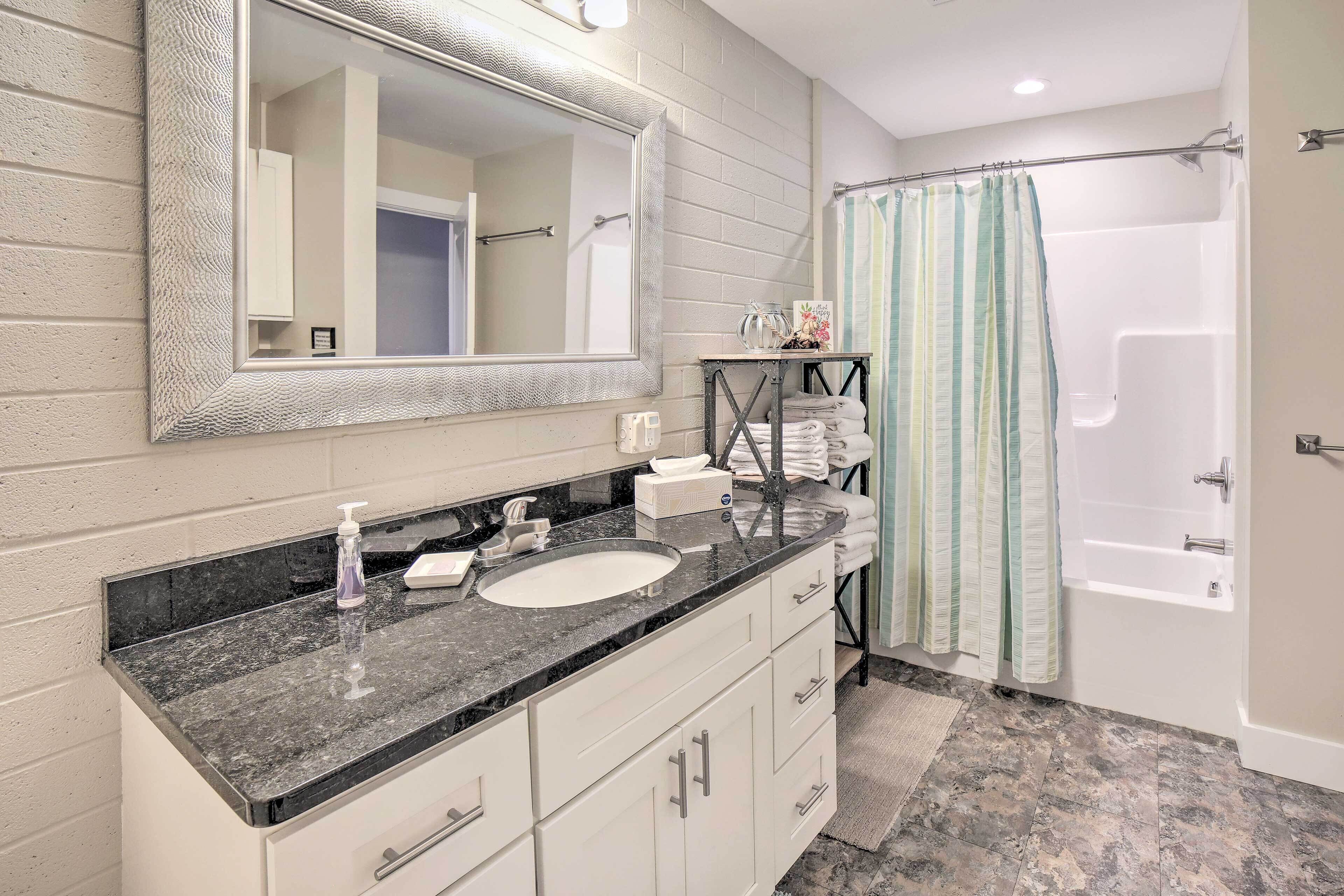 Un bagno con uno specchio grande, un lavandino, una doccia e un portasciugamani.