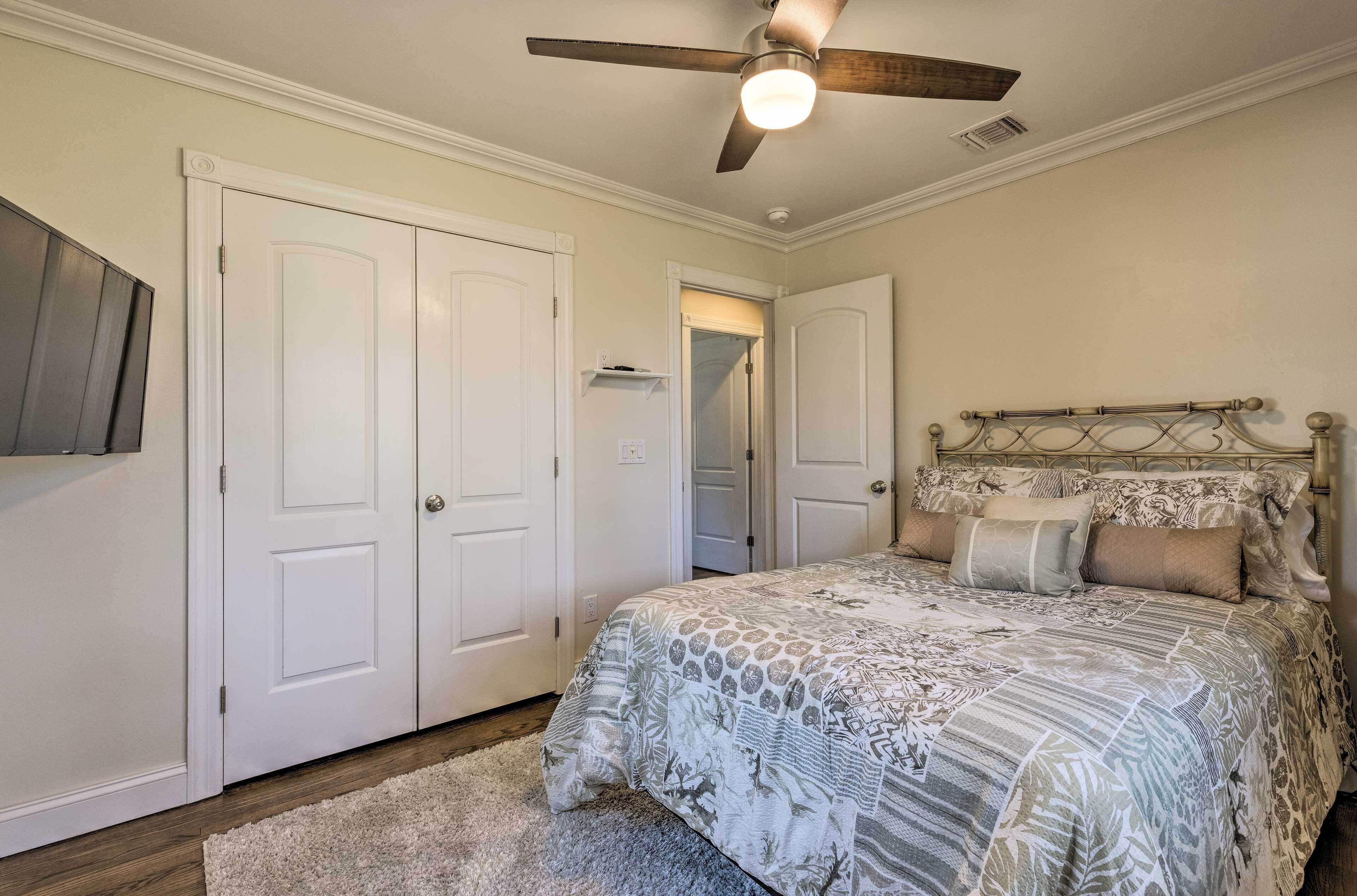 Un dormitorio con una cama, ventilador de techo y puertas blancas.
