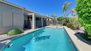 A swimming pool with a clear blue water, surrounded by a landscaped garden with various plants and a palm tree. - Private Pool & Patio: Family Retreat in Mesa (Mesa)