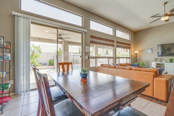 Un vaste espace de salle à manger avec une grande table en bois, un banc intégré et une porte-fenêtre coulissante donnant sur une terrasse extérieure.
