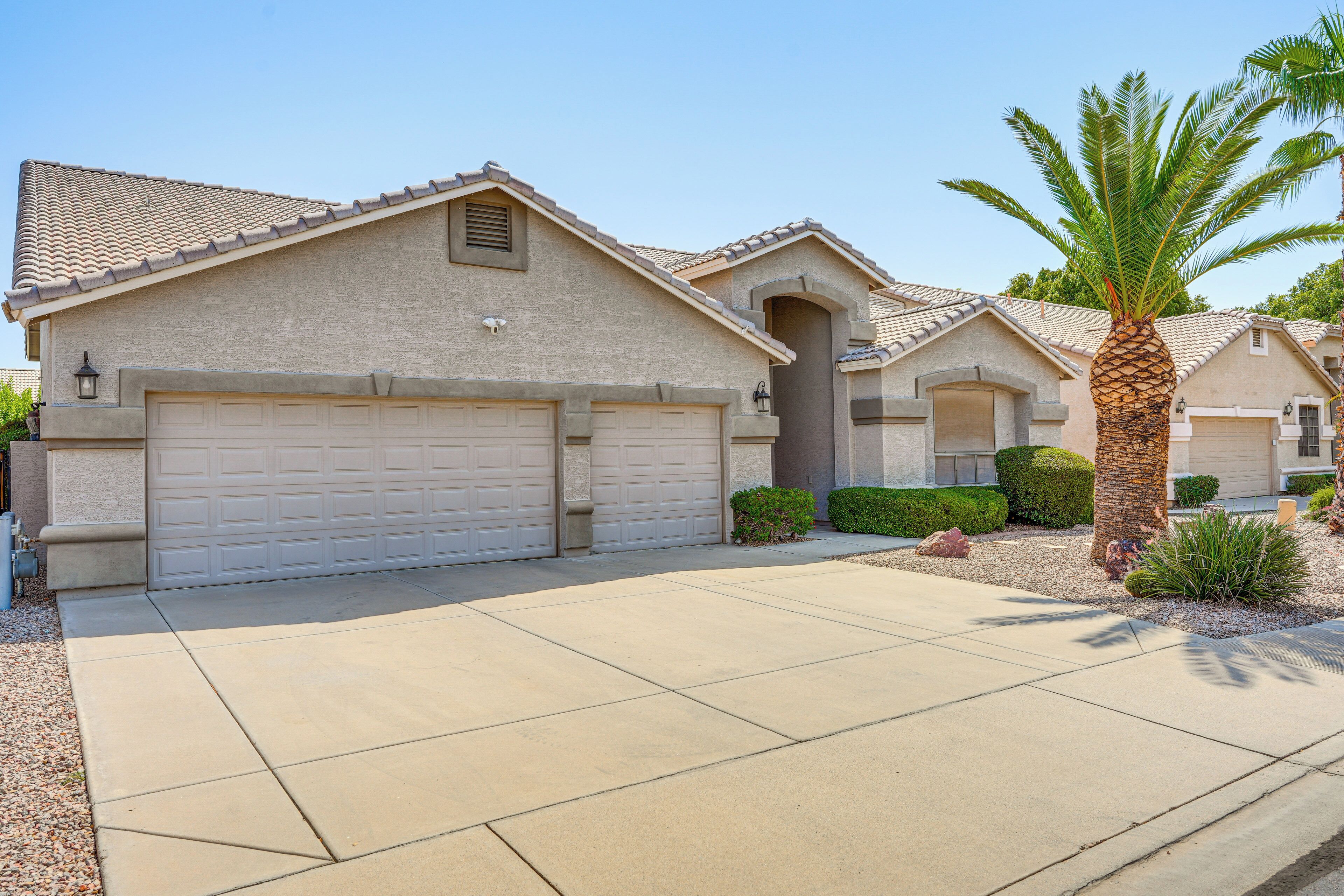 A residential house with a garage, a driveway, and a palm tree.