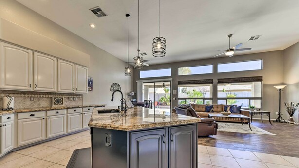 A spacious kitchen with a large island, white cabinets, and a dining area with a sofa and table. - Private Pool & Patio: Family Retreat in Mesa (Mesa)