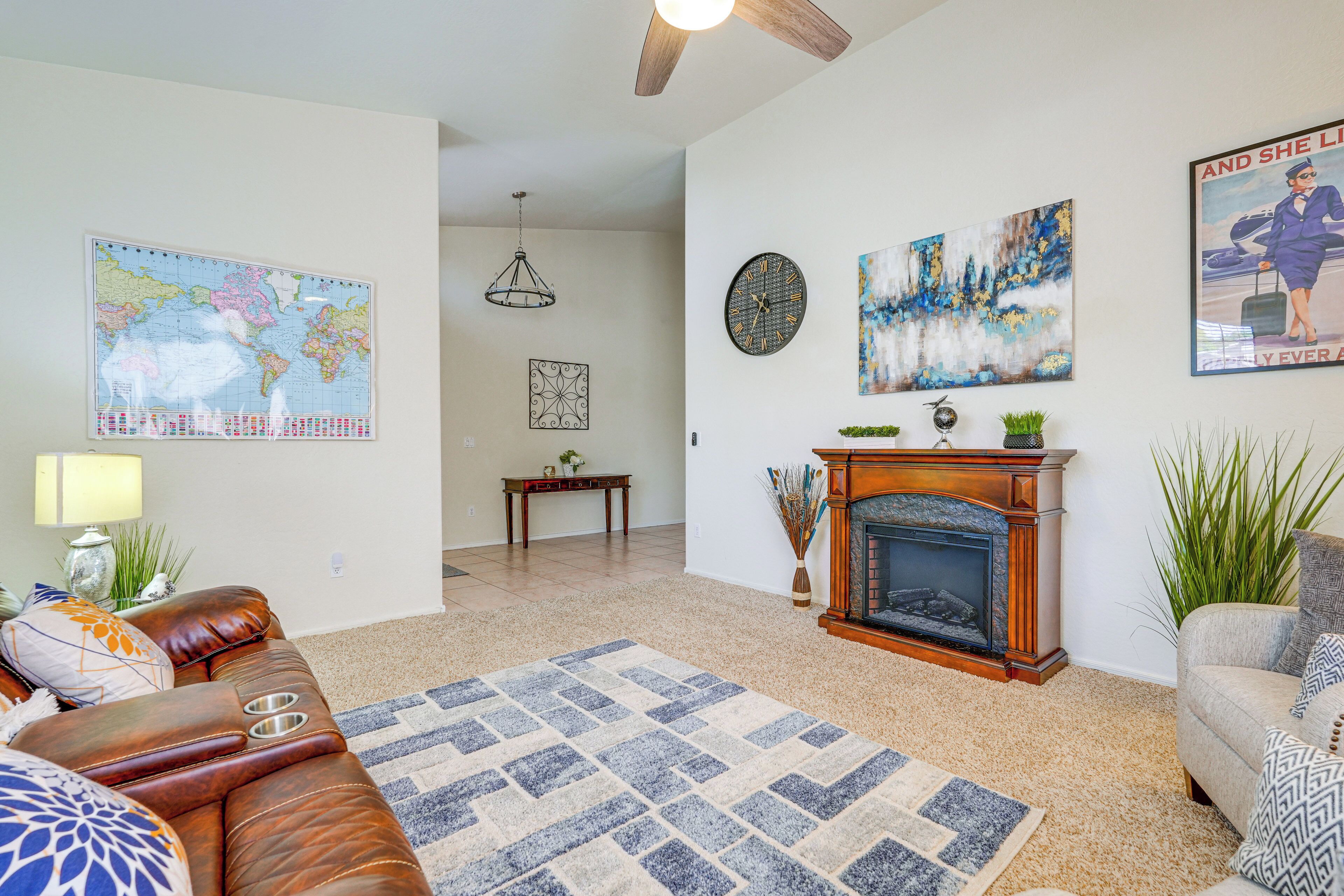 A living room with a fireplace, a world map, and a clock on the wall.
