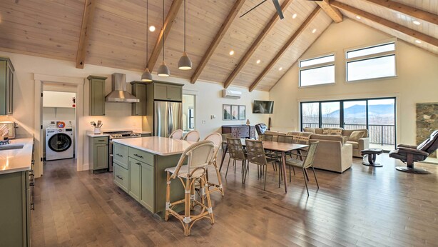 Una cocina amplia con una isla central, comedor con mesa y sillas, y sala de estar con sofá y sillón.